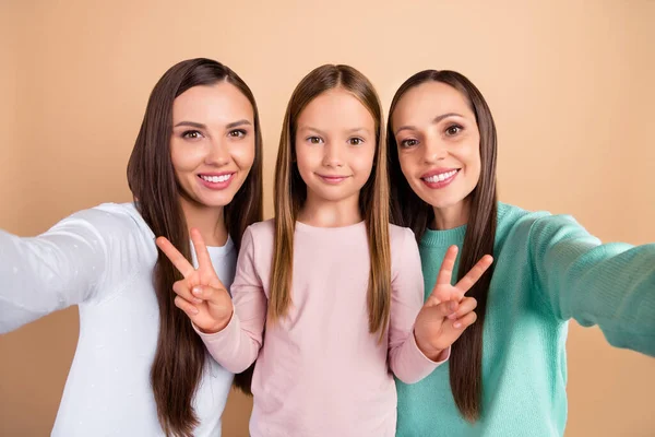 Självporträtt av tre vackra trendiga glada flickor visar v-tecken isolerad över beige pastell färg bakgrund — Stockfoto
