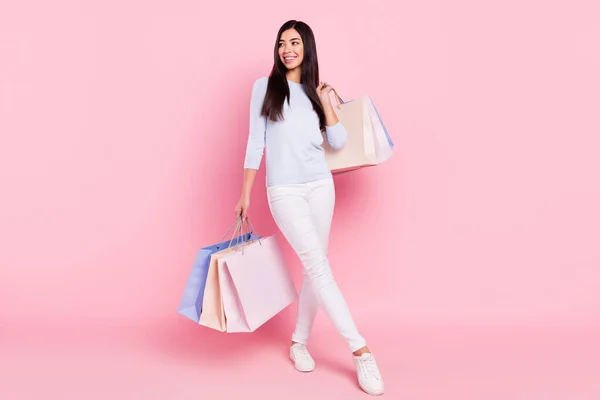 Plná délka tělo velikost pohled atraktivní veselá dívka držení tašky nové věci izolované přes růžové pastelové barvy pozadí — Stock fotografie