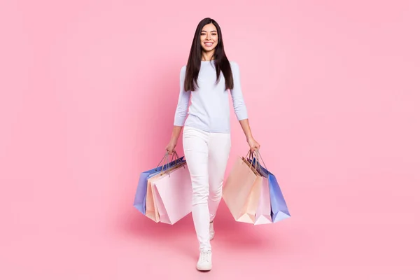 Plná délka tělo velikost pohled na hezké veselá dívka nesoucí tašky maloobchodní věci izolované přes růžové pastelové barvy pozadí — Stock fotografie