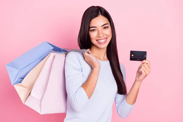 Retrato de menina alegre atraente segurando sacos entrega de ordem de cartão bancário isolado sobre fundo cor pastel rosa — Fotografia de Stock