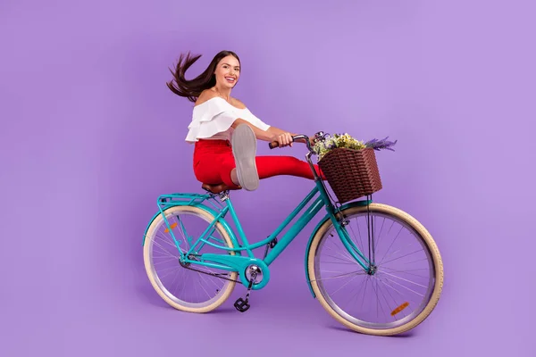 Profil fotografie aktivní dáma těšit jízda na kole zvednout nohy nosit bílou blůzu kalhoty boty izolované fialové barvy pozadí — Stock fotografie