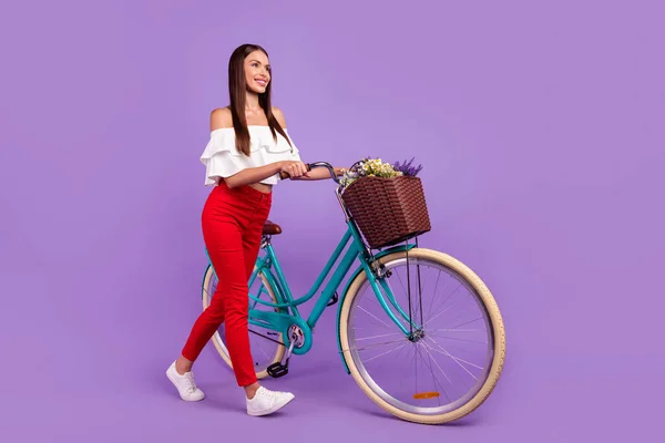 Foto de perfil de la señora despreocupada paseo en bicicleta usar pantalones de blusa blanca zapatillas aisladas color púrpura fondo —  Fotos de Stock