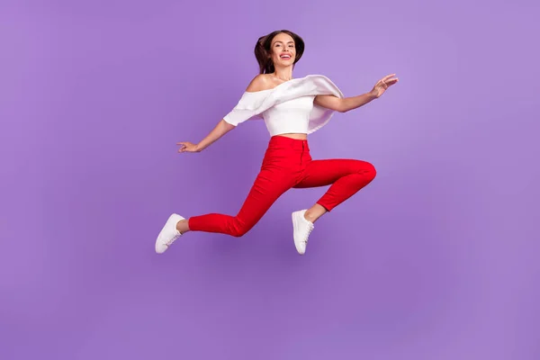 Foto de adorável alegre senhora salto desfrutar de voo ir mover desgaste branco blusa calças isoladas cor violeta fundo — Fotografia de Stock