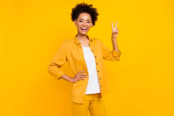 Foto de la joven mujer negra emocionada mostrar paz fresco símbolo de la victoria v-signo aislado sobre fondo de color amarillo — Foto de Stock