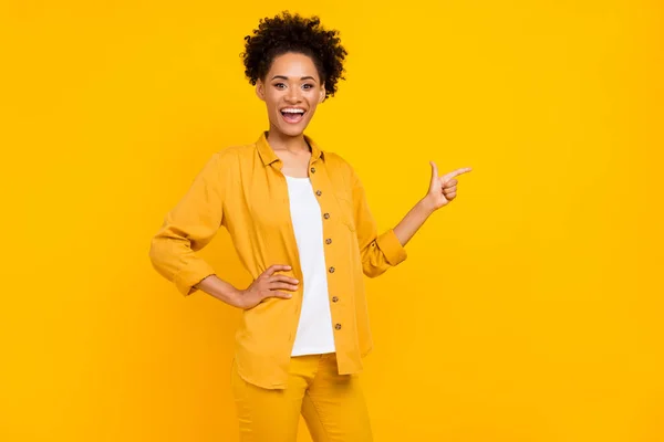 Foto de joven encantadora chica africana dedo dedo vacío espacio anuncio seguir sugerir venta aislado sobre fondo de color amarillo — Foto de Stock