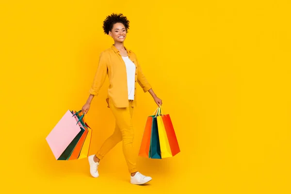 Foto lateral de perfil de tamaño completo de la joven afro chica ir a pie tienda de compras aislado sobre fondo de color amarillo — Foto de Stock