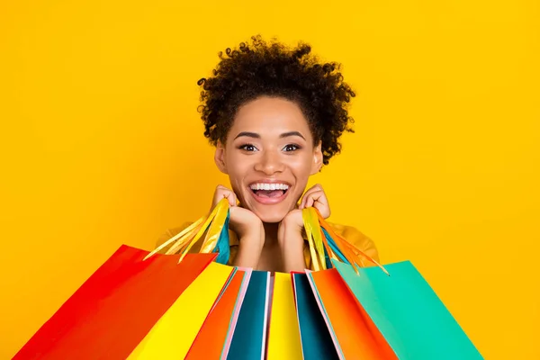 Φωτογραφία του νεαρού χαρούμενα μαύρο κορίτσι καλή διάθεση shopaholic πώληση εμπορικό κέντρο τσάντα απομονώνονται σε κίτρινο χρώμα φόντο — Φωτογραφία Αρχείου