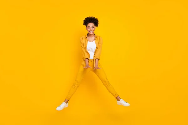 Foto de longitud completa de la joven alegre chica negra divertirse saltar hasta volar aire aislado sobre fondo de color amarillo — Foto de Stock