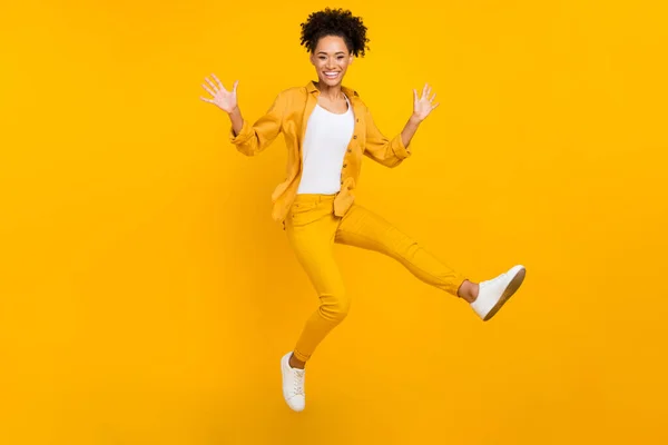 Volledige lengte foto van jonge vrolijke afro meisje springen golf hallo vliegen lucht geïsoleerd over gele kleur achtergrond — Stockfoto