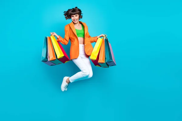 Полная длина фото молодой веселой женщины прыгать вверх воздушный трюм торговых мешков наслаждаться изолированы на голубом фоне цвета — стоковое фото