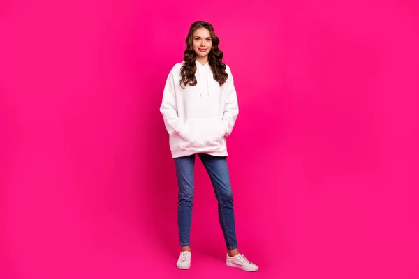 Foto av glada positiva vackra dam händer fickor bära vit hoodie jeans skor isolerad rosa färg bakgrund — Stockfoto