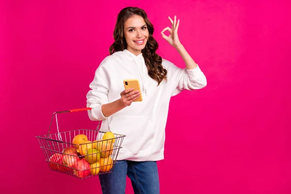 Foto de menina feliz sorriso loja loja comprar comida mostrar tudo bem bem escolha sinal isolado sobre cor rosa fundo — Fotografia de Stock