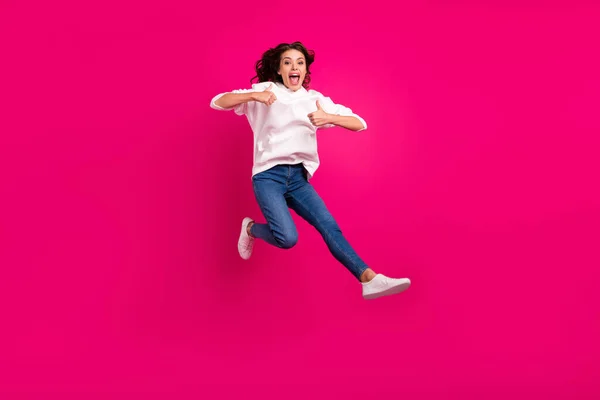 Full length photo of young girl happy positive smile jump up show thumbs-up like cool ad isolated over pink color background — Stock Photo, Image