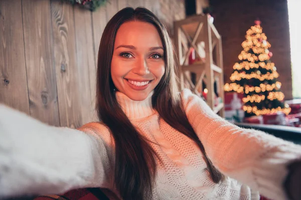 Foto retrato mujer sonriente usando suéter de punto sonriendo sentado en el sofá tomando selfie — Foto de Stock