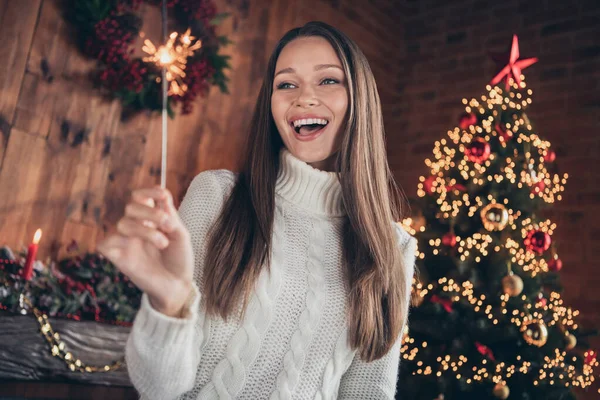 Foto de señora joven bastante emocionada usar jersey blanco sonriendo sosteniendo fuego de bengala en el interior casa casa habitación — Foto de Stock