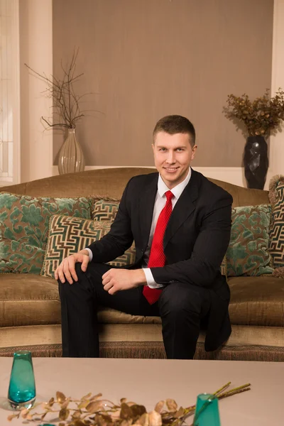 Thoughtful businessman. thoughtful young man in formalwear sitting on the couch and smiling — Stock Photo, Image