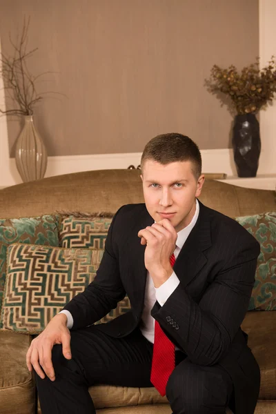 Thoughtful businessman. thoughtful young man in formalwear sitting on the couch and smiling — Stock Photo, Image