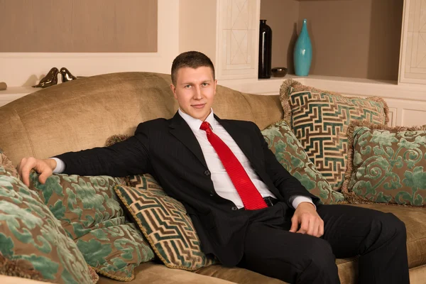 Successful handsome man sitting on the couch. young businessman resting after work in his posh apartment. man in a business suit — Stock Photo, Image