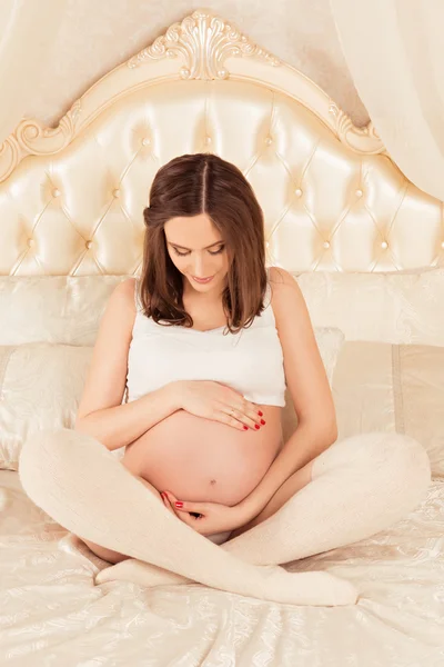 Schöne schwangere Frau umarmt ihren Bauch — Stockfoto