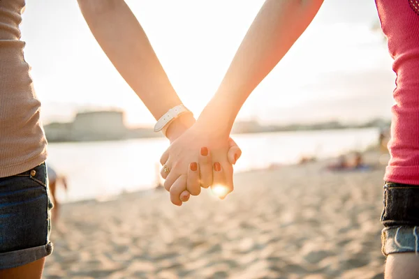 Jenta som holder hender på stranda – stockfoto
