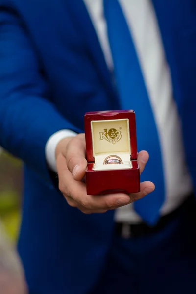 Imagem de corte do noivo segurando uma caixa com anéis de casamento — Fotografia de Stock