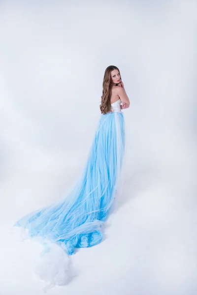Menina bonita em um vestido longo azul com pluma — Fotografia de Stock