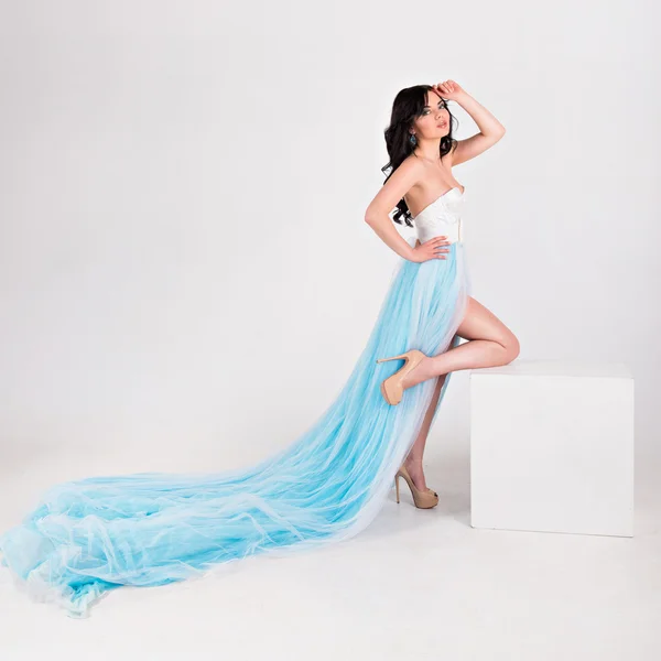 Menina bonita em um vestido longo azul com pluma — Fotografia de Stock