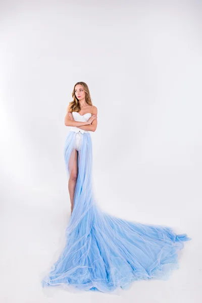 Menina bonita em um vestido longo azul com pluma em um backgr branco — Fotografia de Stock