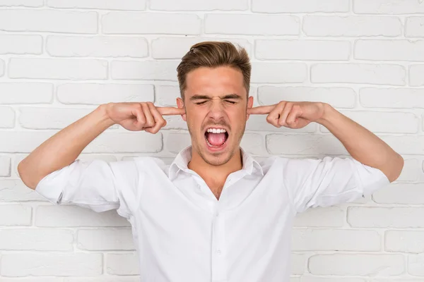 This is too loud! Frustrated man holding fingers in his ears — Stock Photo, Image