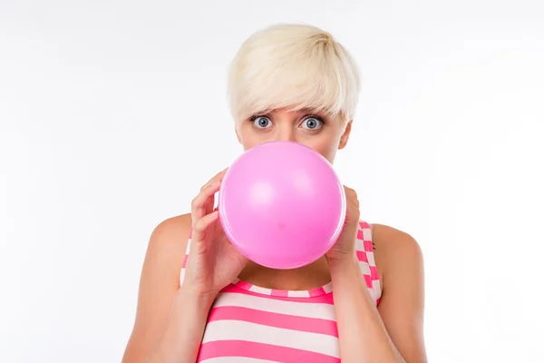 Счастливая девушка надувает розовый шарик — стоковое фото