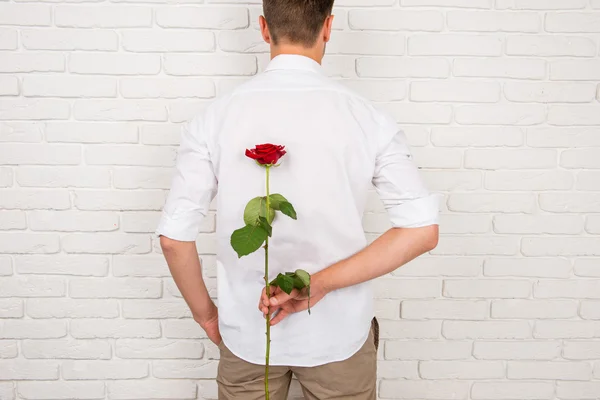 Un hombre escondiendo detrás de su espalda una rosa roja — Foto de Stock