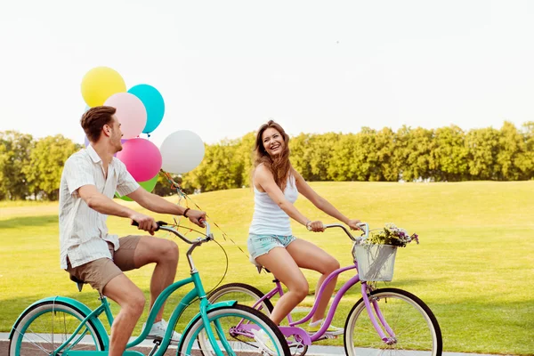 Couple in love together to ride a bicycle with ballons — Stock Photo, Image