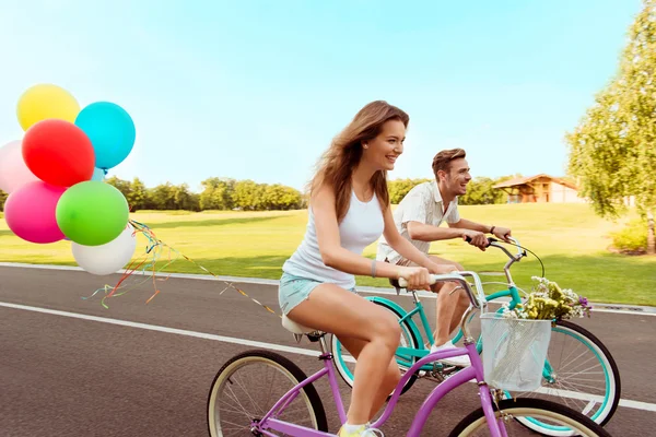 Coppia innamorata in sella a una corsa in bicicletta con palloncini — Foto Stock