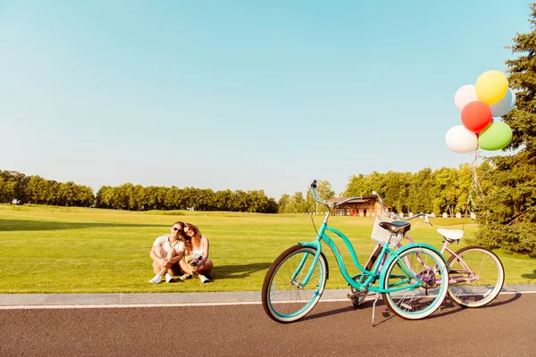 Onların bisiklet yakınındaki Çimenlikte oturan genç Çift — Stok fotoğraf