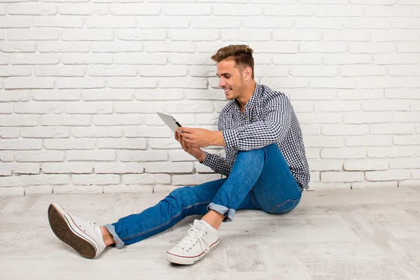 Человек, сидящий на полу с цифровым планшетом — стоковое фото