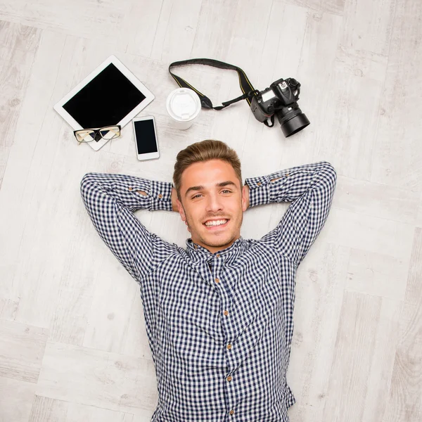 Vista superior del hombre acostado en el suelo con cámara, tableta, café — Foto de Stock