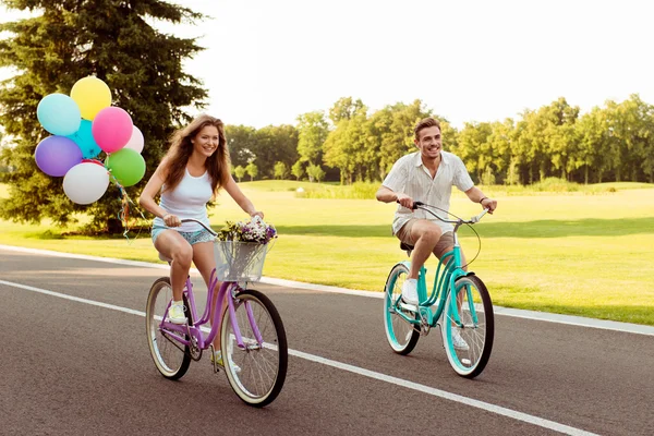 Gelukkige jonge paar in liefde fietsen met ballonnen — Stockfoto