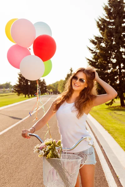 Счастливая девушка на велосипеде с цветами — стоковое фото