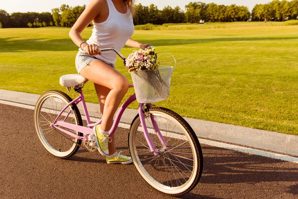 Menina andando de bicicleta com flores — Fotografia de Stock