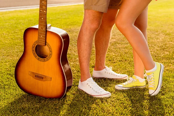 Man en vrouw benen met gitaar. Paar verliefd op het gazon — Stockfoto