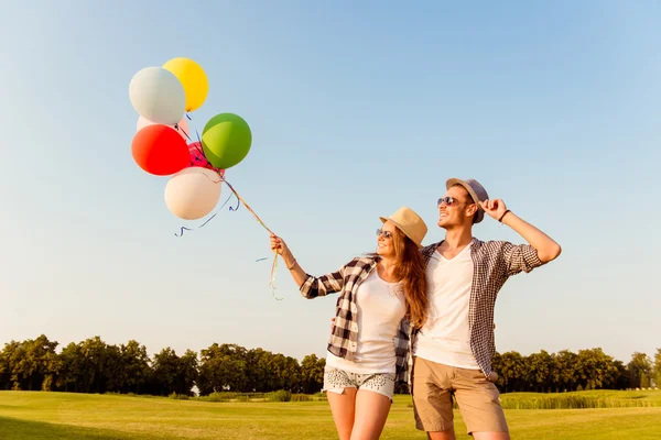 Пара влюбленных гуляющих с воздушными шарами — стоковое фото