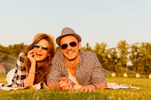 Liebespaar liegt mit Brille und Hut im Gras — Stockfoto