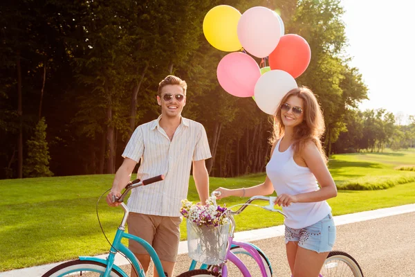 Пара влюбленных на велосипедах с воздушными шарами и цветами — стоковое фото
