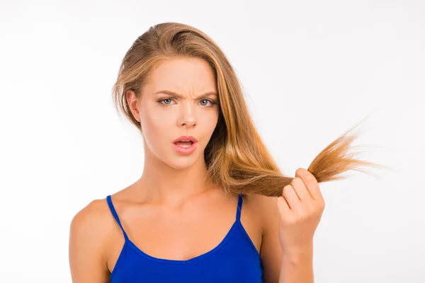 Jonge vrouw kijkt naar gespleten eindjes. Beschadigd lang haar — Stockfoto