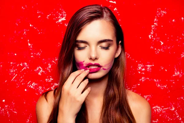 Szexi modell, piros háttéren, dörzsölés rúzs, és lehunyta szemét — Stock Fotó