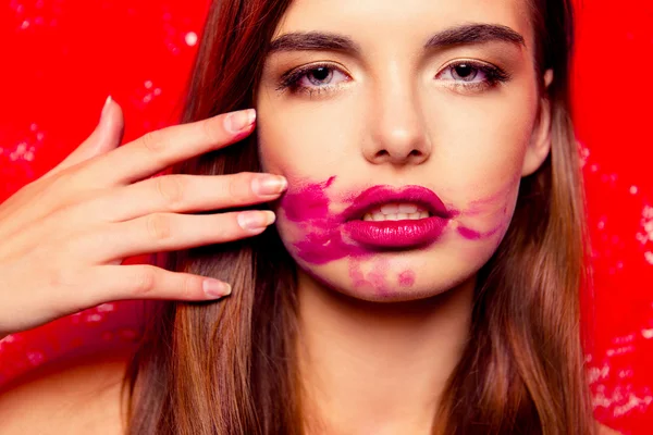 Hermosa chica sobre un fondo rojo frotando lápiz labial — Foto de Stock