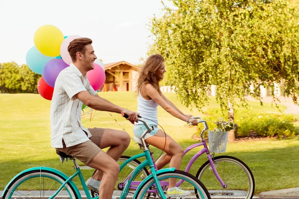 Casal apaixonado juntos para andar de bicicleta com balões — Fotografia de Stock