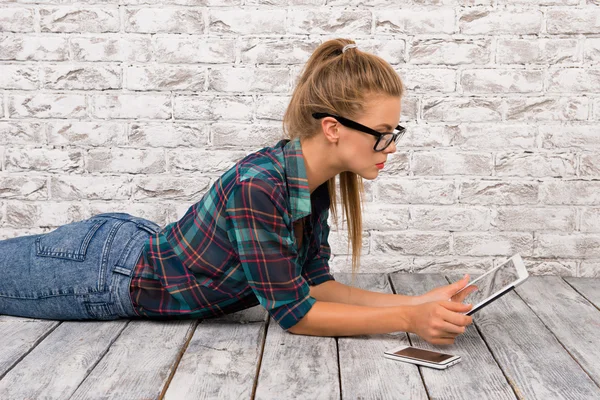 Ragazza sdraiata sul pavimento e che lavora in un tablet — Foto Stock