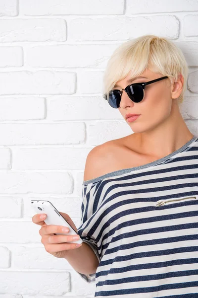 Junges Mädchen mit Brille liest SMS am Telefon — Stockfoto