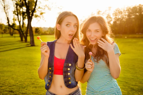 Two astonished amusing sexy girls with lollipops — Stock Photo, Image